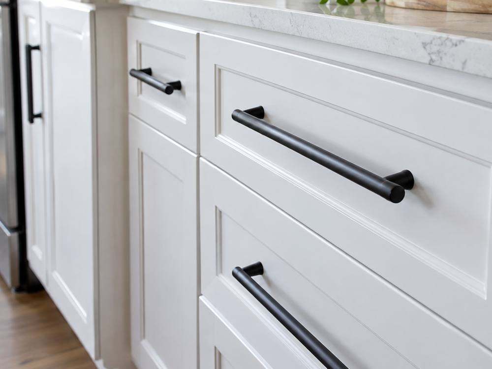 Close view of black bar pulls on white painted shaker drawers